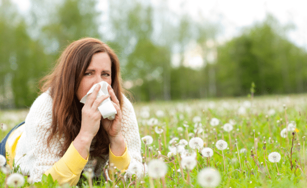 Unhappy middle age woman with hay fever and handkerchief lying in the grass