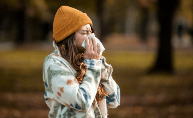 Woman sneezing in handkerchief at autumn